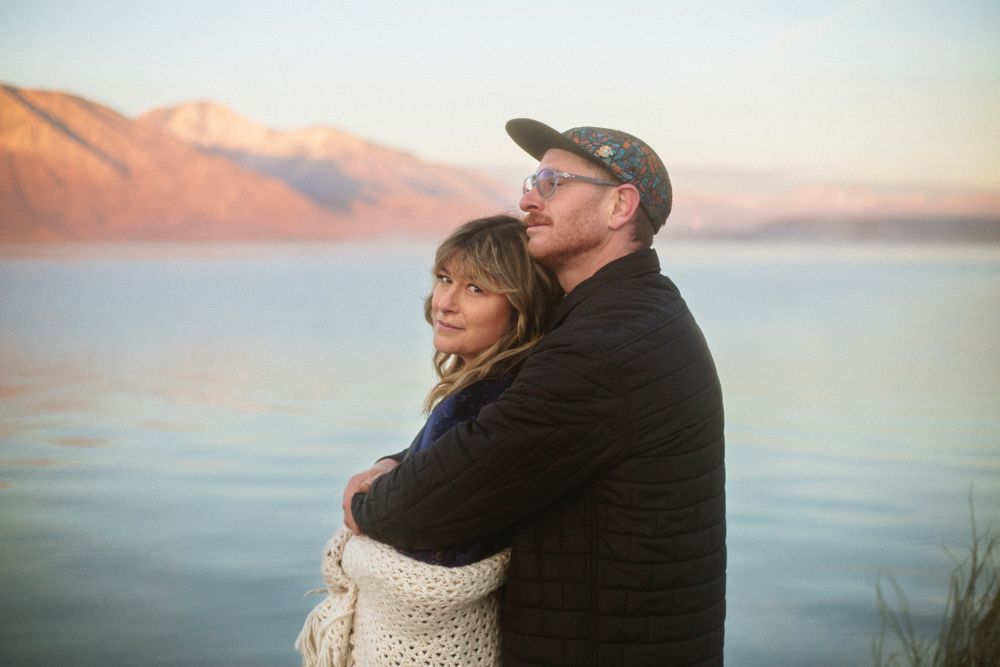 portrait of a couple hugging with lake Crowley in the background