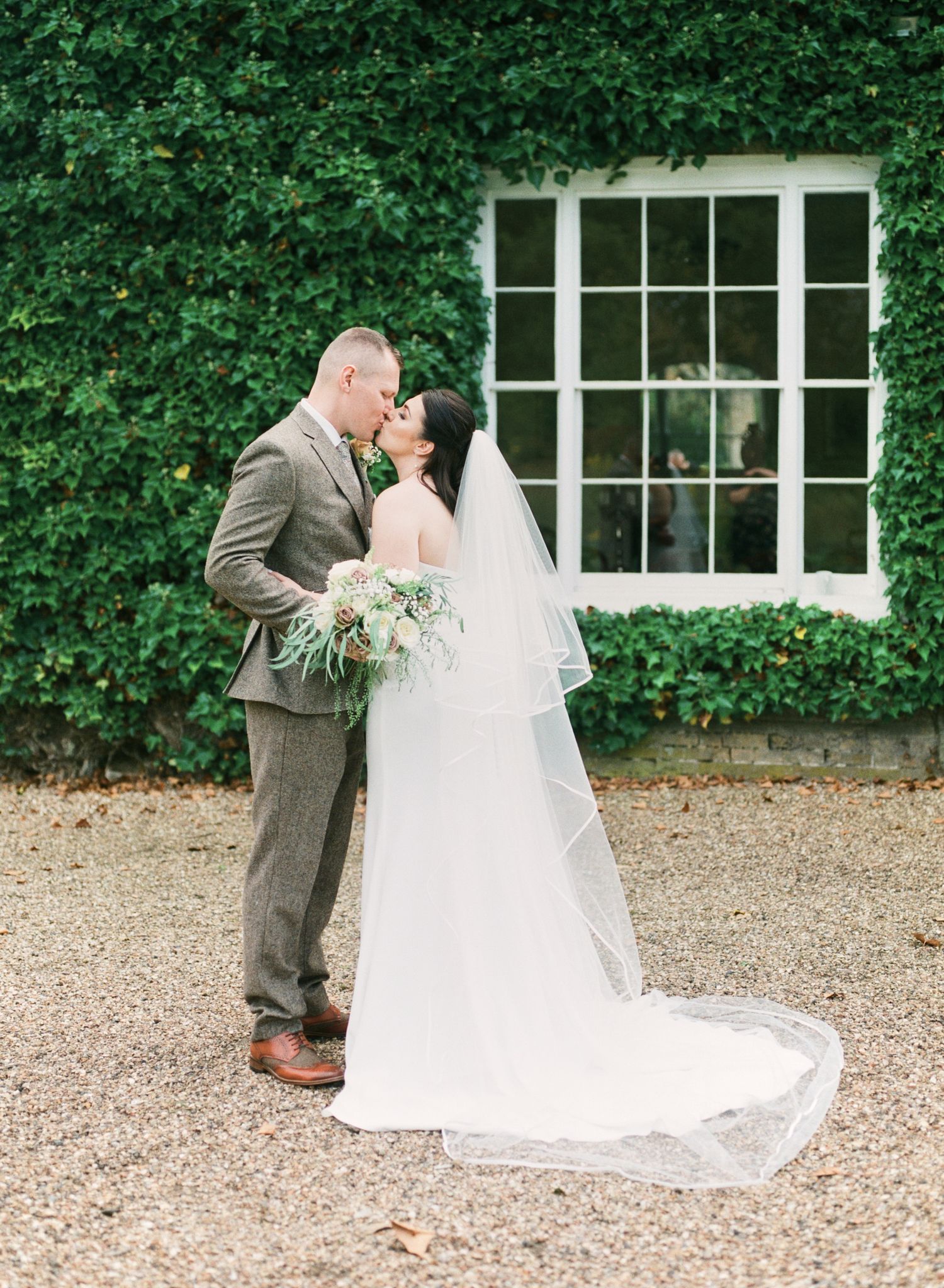bride & groom share a kiss in the gardens of Bressingham Hall, Norfork. by Faye Amare photography on film