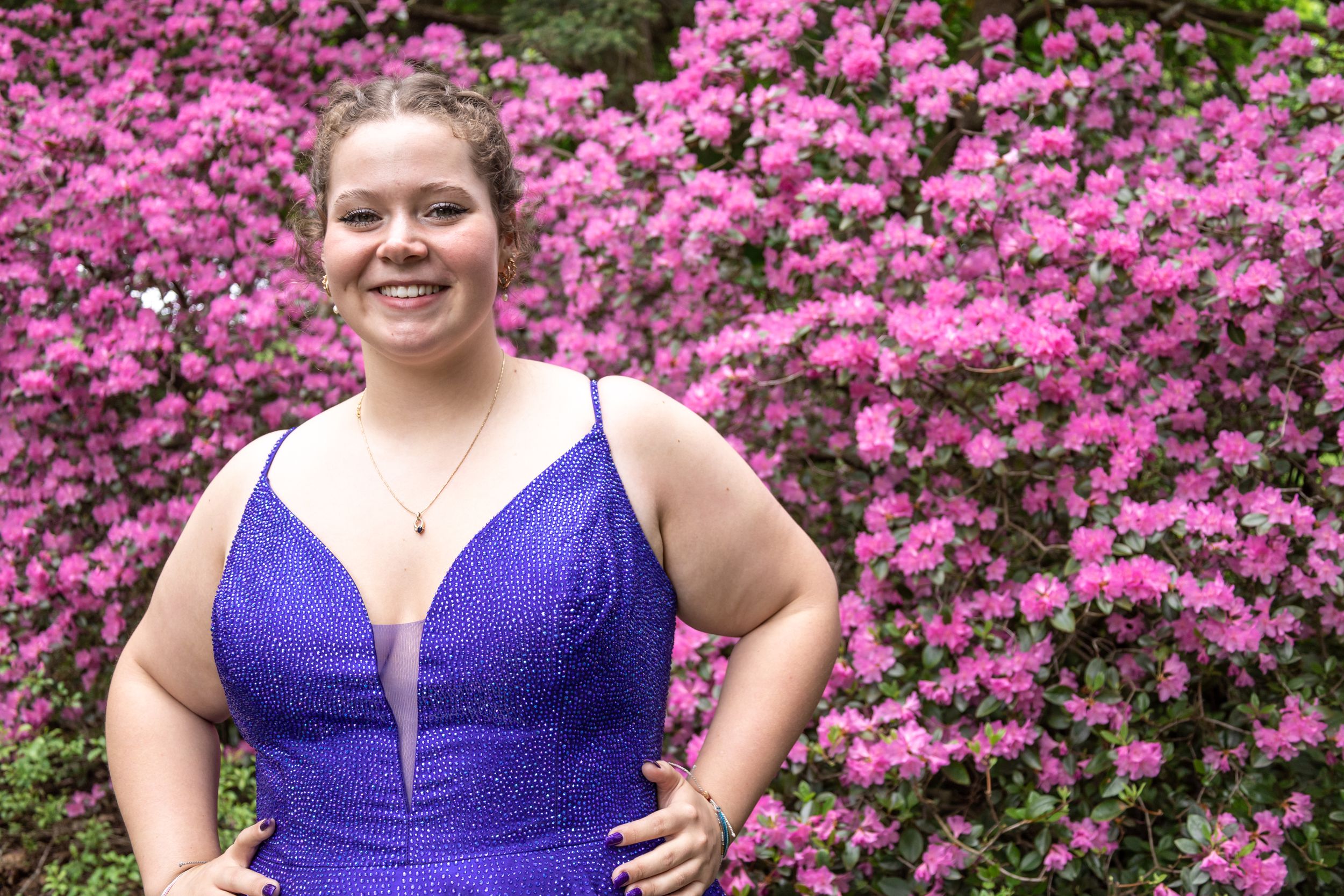 A close-up portrait in a sparkly purple formal dress with pink flowering background.