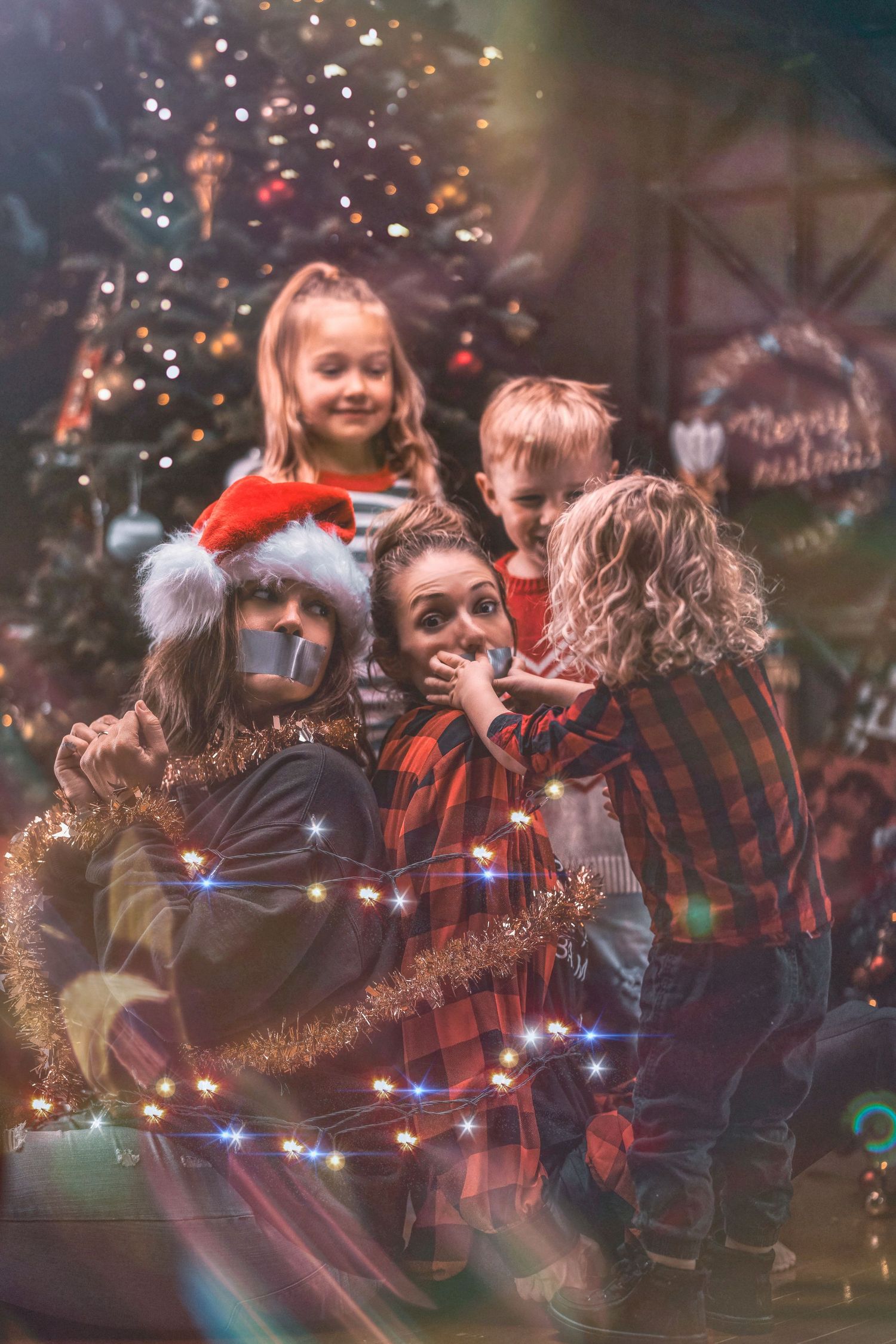 Children gathered around Christmas tree with festive lights and holiday decorations.