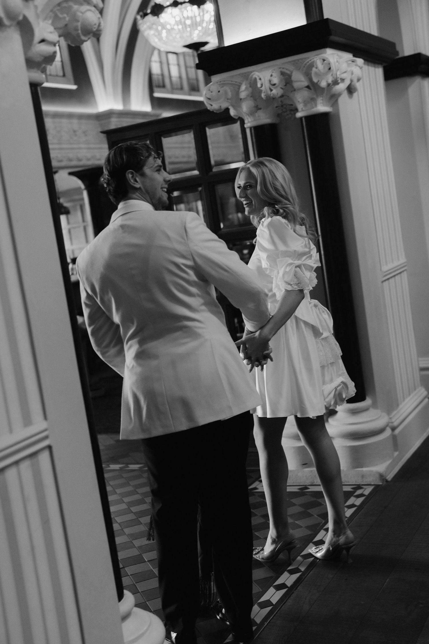 bride and groom laughing holding hands as they leave the Randolph hotel in oxford