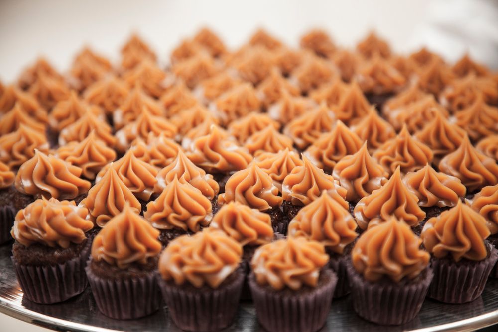 Rows of chocolate cupcakes topped with swirled brown frosting arranged on a platter.