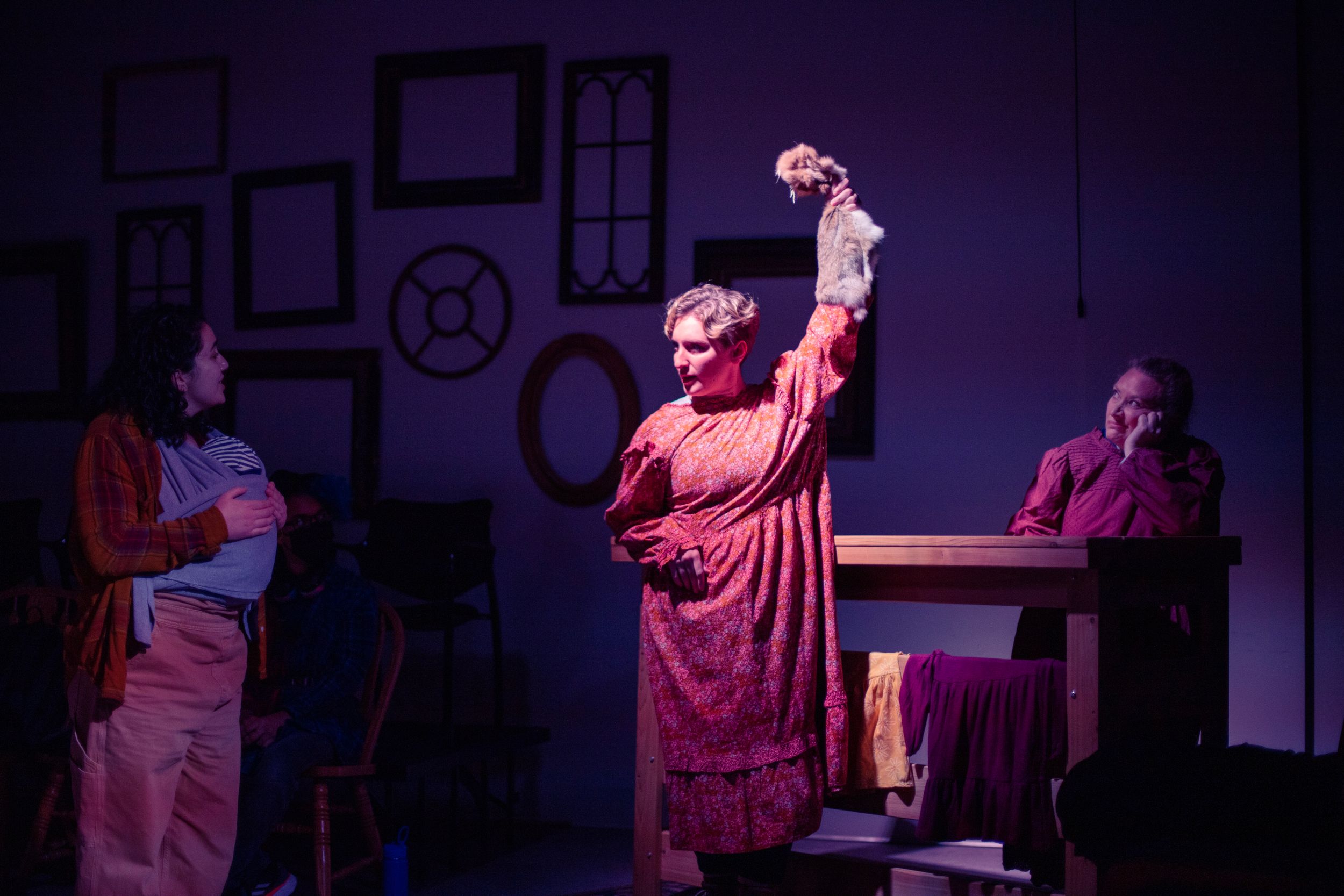 Performers act in a dramatic scene with wall decorations and dramatic lighting on stage. Production photo from Mary's Wondrous Body in 2022.