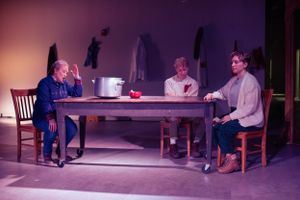 Actors sit around a wooden table in a purple-lit theatrical scene. Production photo from Mary's Wondrous Body in 2022.