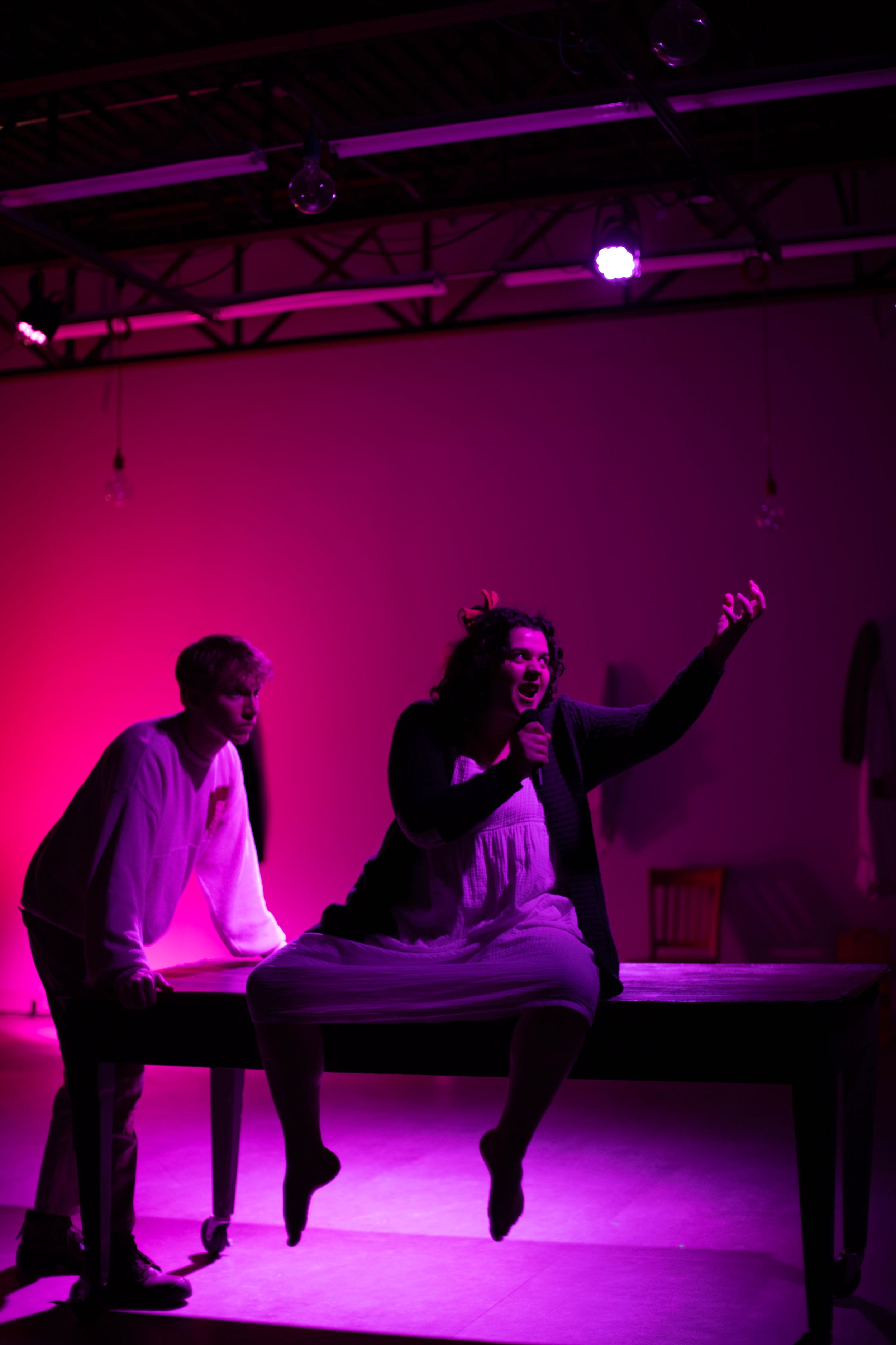 Two performers create a dynamic scene on stage under vibrant pink theatrical lighting. From Mary's Wondrous Body in 2022, Elision Playhouse.