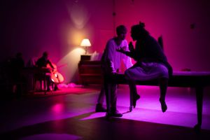 Performers create silhouettes against magenta stage lighting in an intimate theater scene. From Mary's Wondrous Body in 2022.