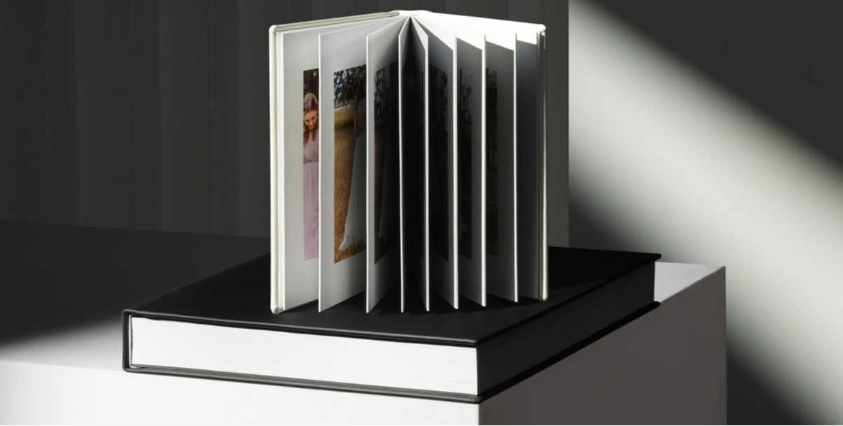 Professional wedding photo album with thick pages displayed in dramatic lighting.