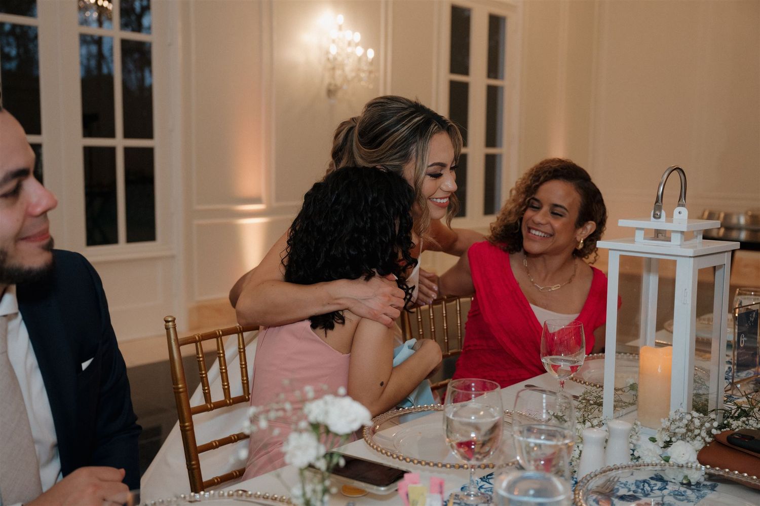 Wedding reception guests share laughter and conversation around an elegantly decorated dinner table.