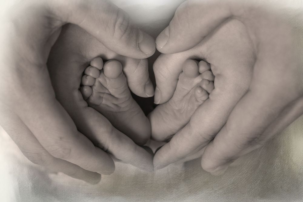 Infant's feet in parents hands forming a heart