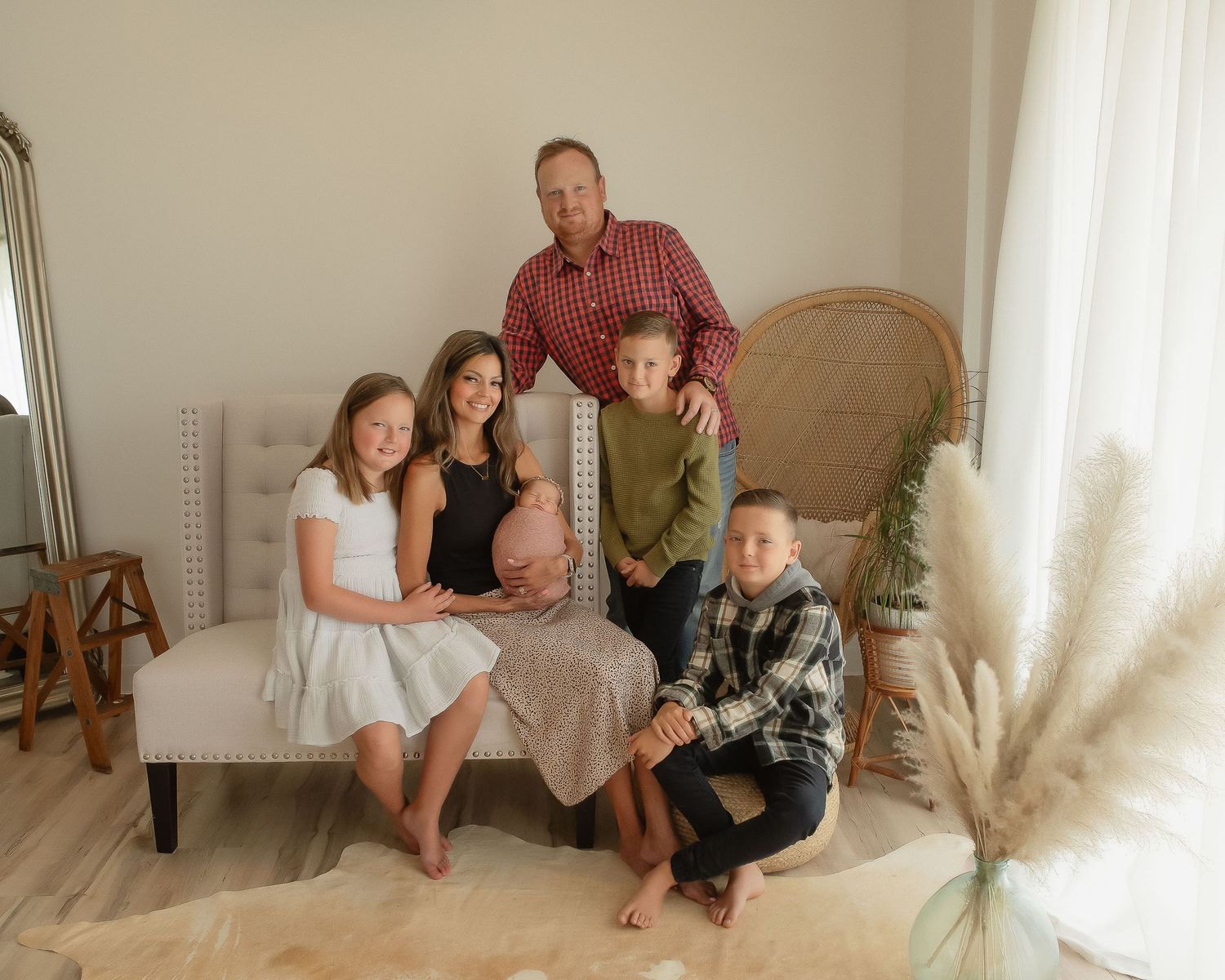 Family portrait in neutral toned room with wicker chair and pampas grass decor.