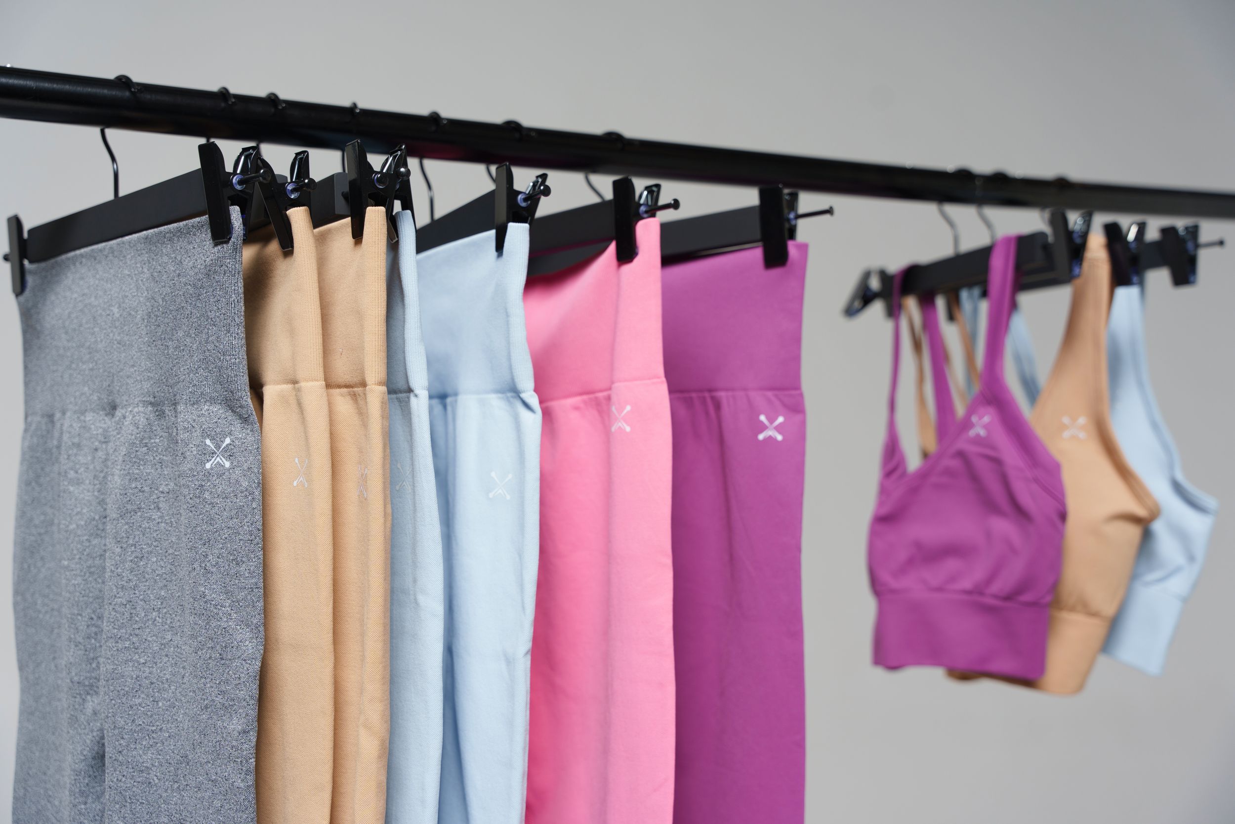 Colorful array of athletic leggings and sports bras hanging on a clothing rack.
