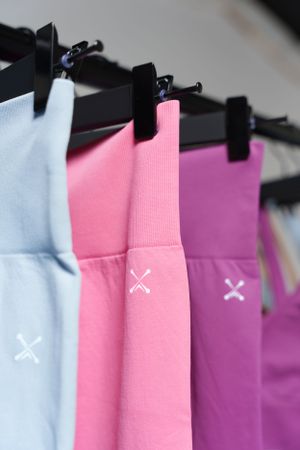 Close-up of pastel colored athletic wear with X logo detail hanging on retail display.