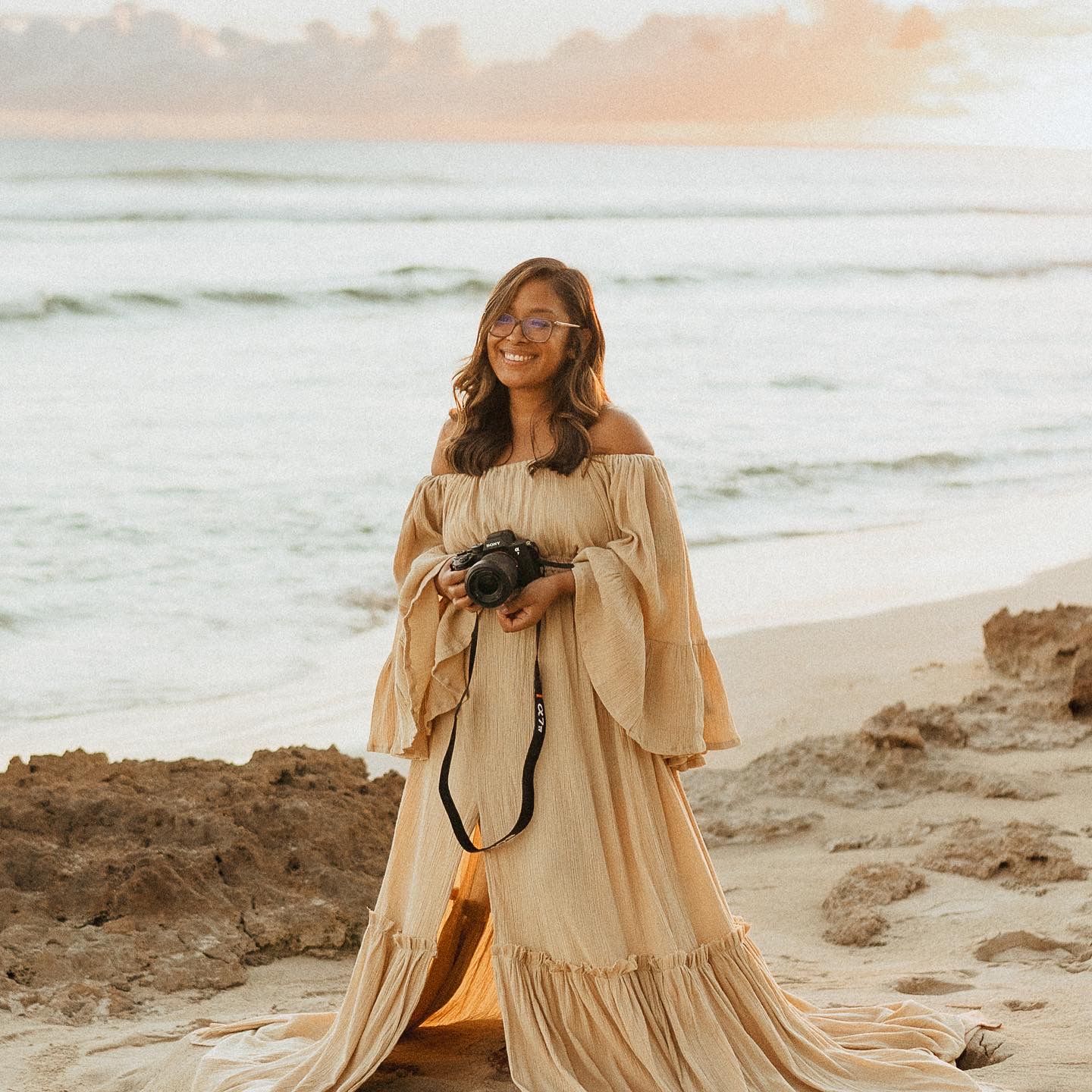 Photographer Kelly Pagan standing on the beach with her camera on Oahu in Hawaii