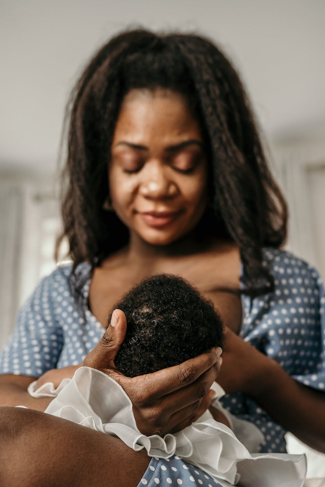 close-up of a mother's hand holding her newborn daughter's head whilst she is breast-feeding