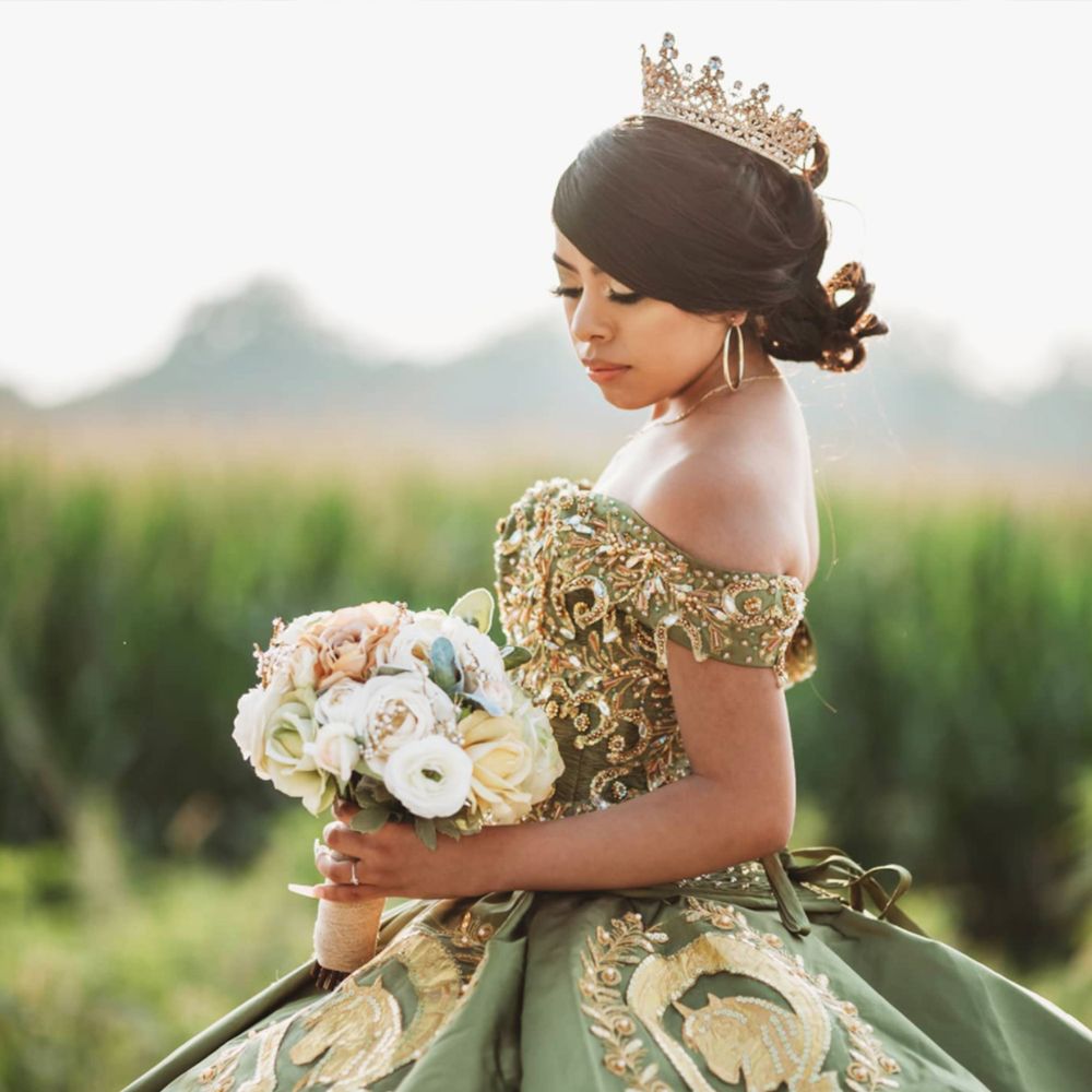 Ornate mint green ball gown with gold details photographed in a rural outdoor setting.