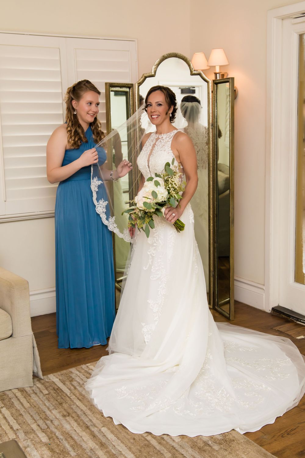 Wedding party members in blue and white dresses gather for photos in elegant indoor setting.