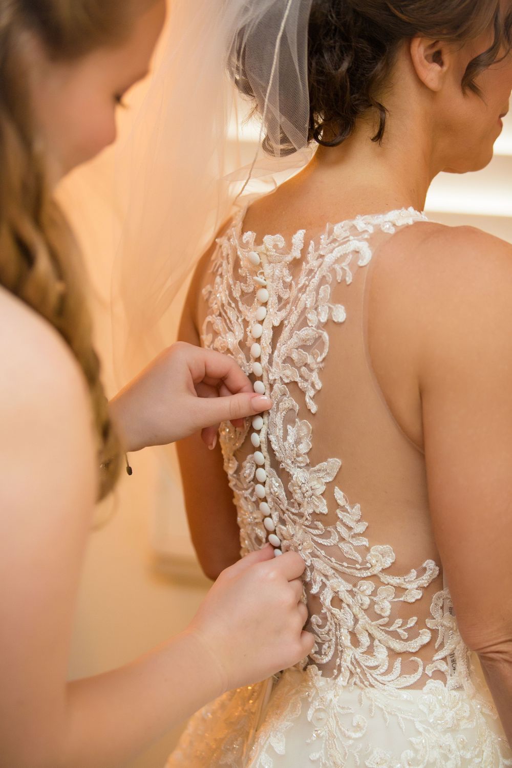 Close-up of intricate lace detailing on the back of a white wedding gown.