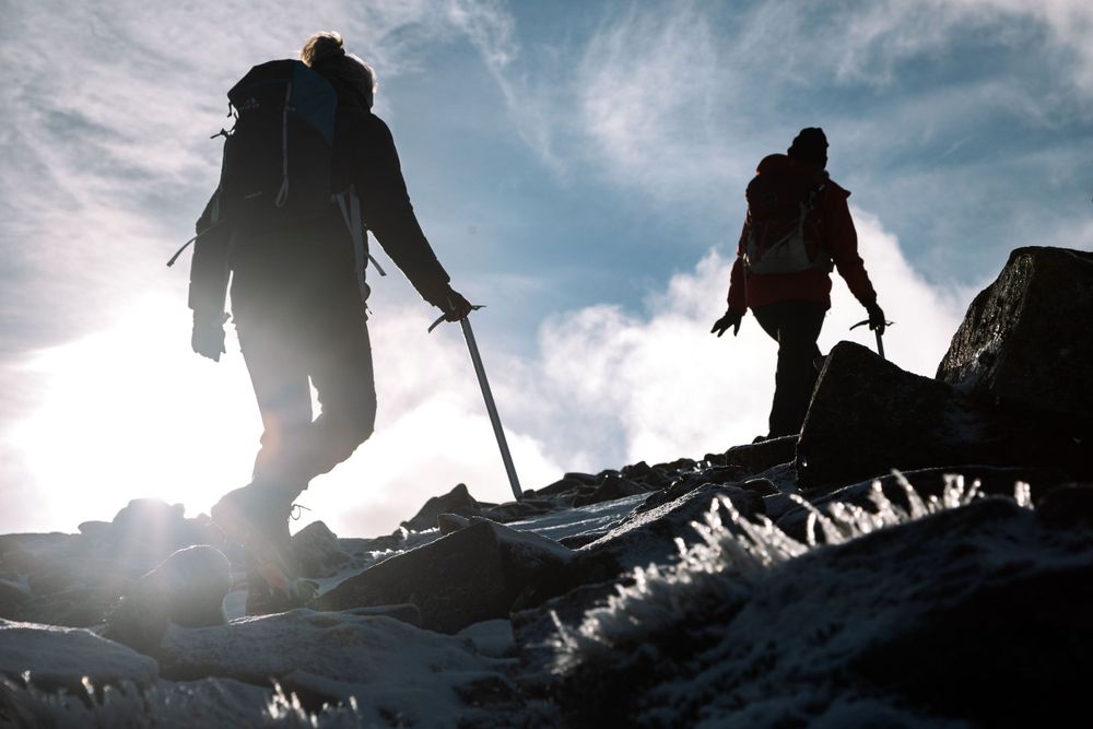 Silhouette of Mollie Hughes mountaineer and client hiking scottish mountain with ice axes