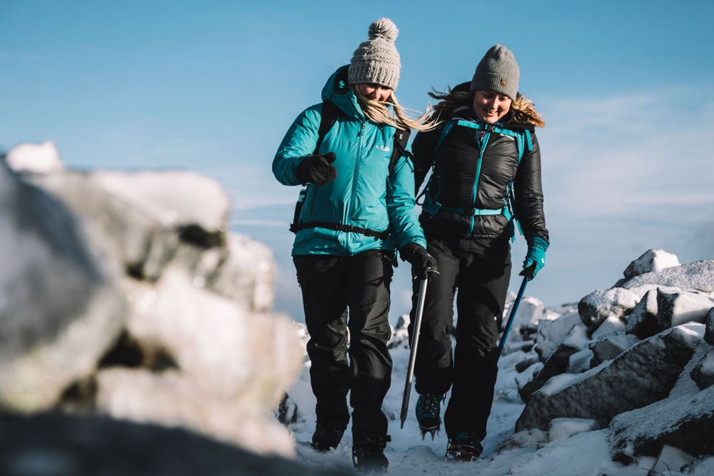 Mollie Hughes mountaineer guiding client walking on icey rocky hilltop