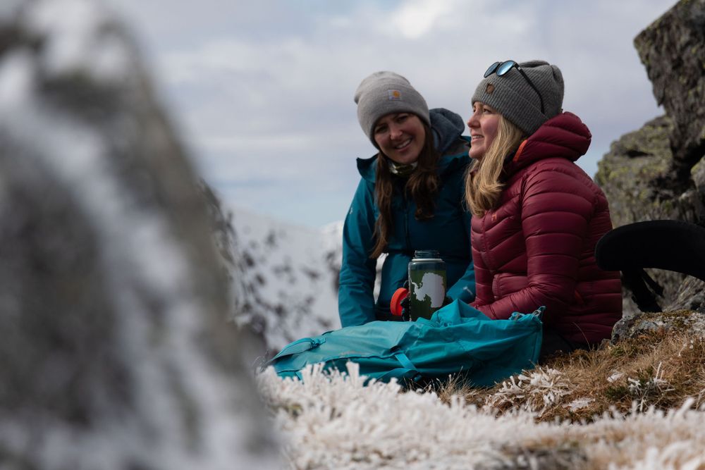 Mollie Hughes mountaineer and client laugh sitting atop scottish mountain having a rest