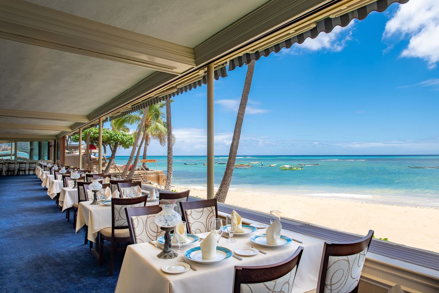 An elegant beachfront restaurant with white-clothed tables overlooks a stunning turquoise ocean and palm trees.
ミシェルズレストランでのパーティー