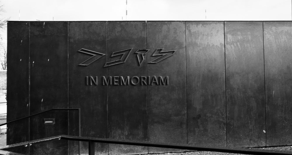 Black and white photo of a dark metal wall with Mercedes-Benz SLR In Memoriam text.
