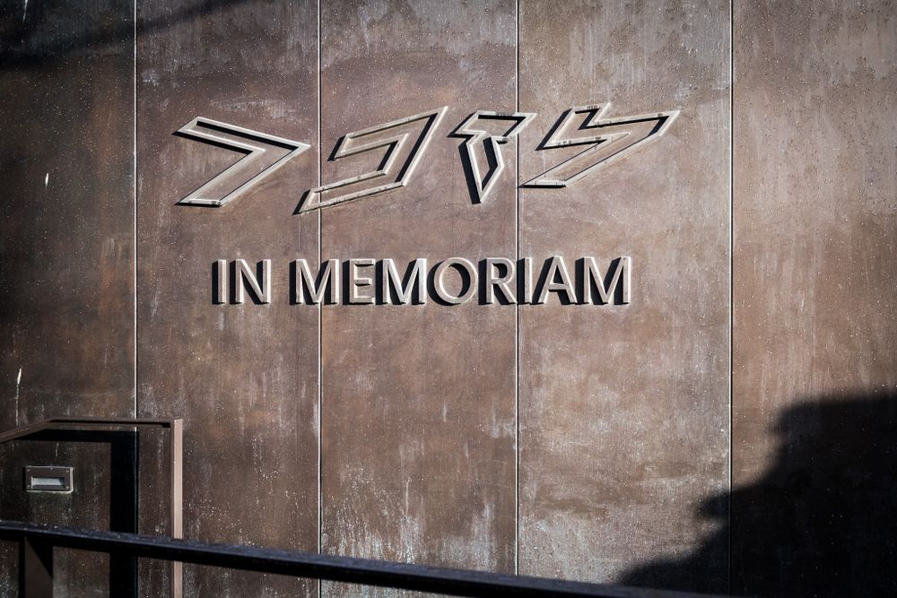 Close-up of weathered metal Mercedes-Benz SLR In Memoriam memorial wall with shadow detail.