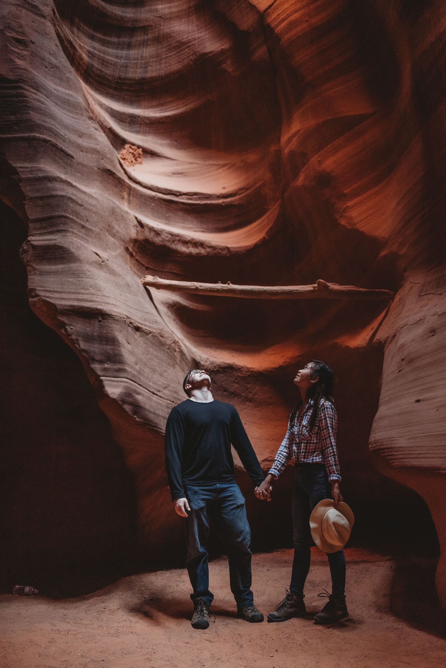 Visitors admiring the smooth, curved walls inside a dimly lit slot canyon.