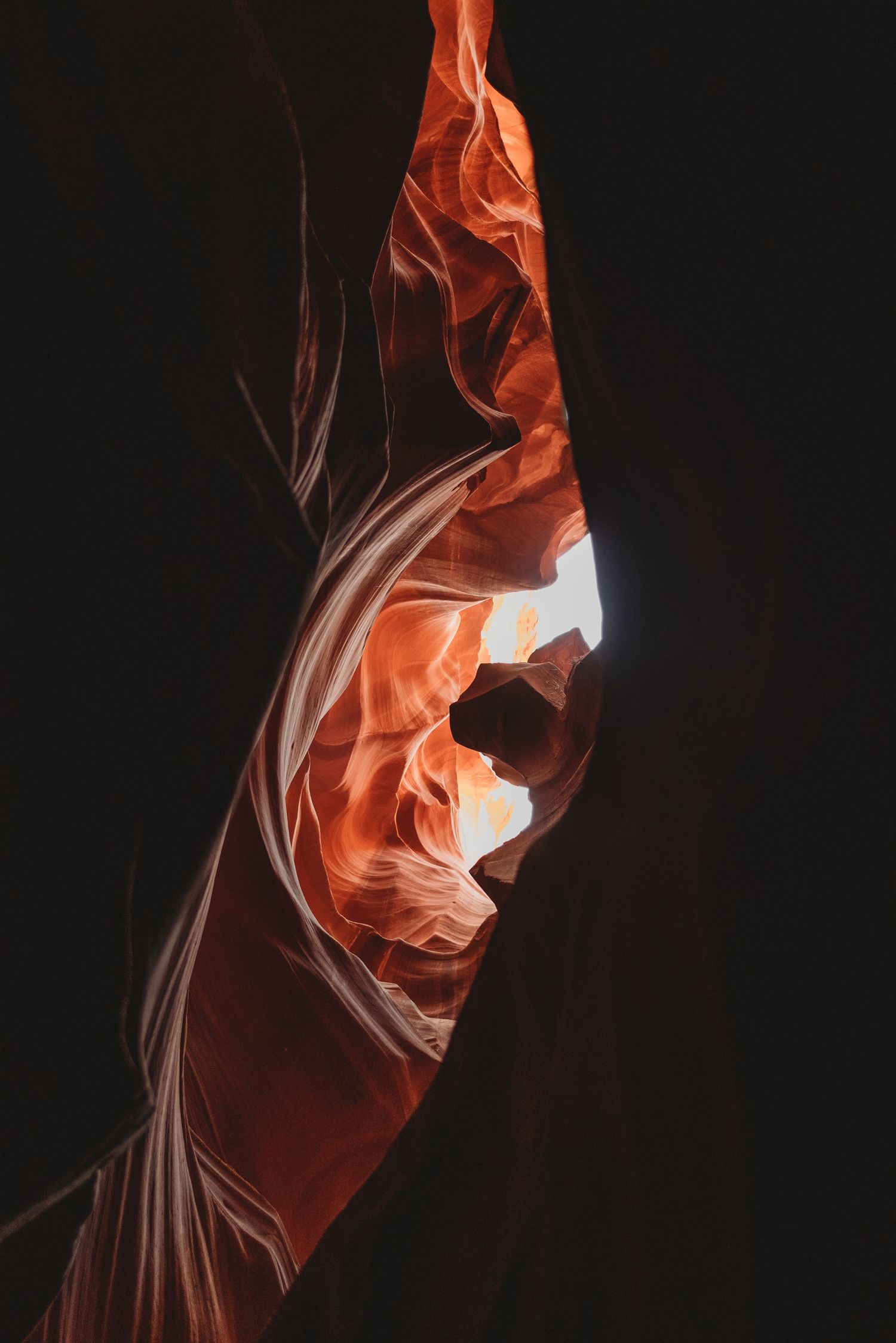 Sunlight streams through openings in Antelope Canyon creating glowing orange patterns.