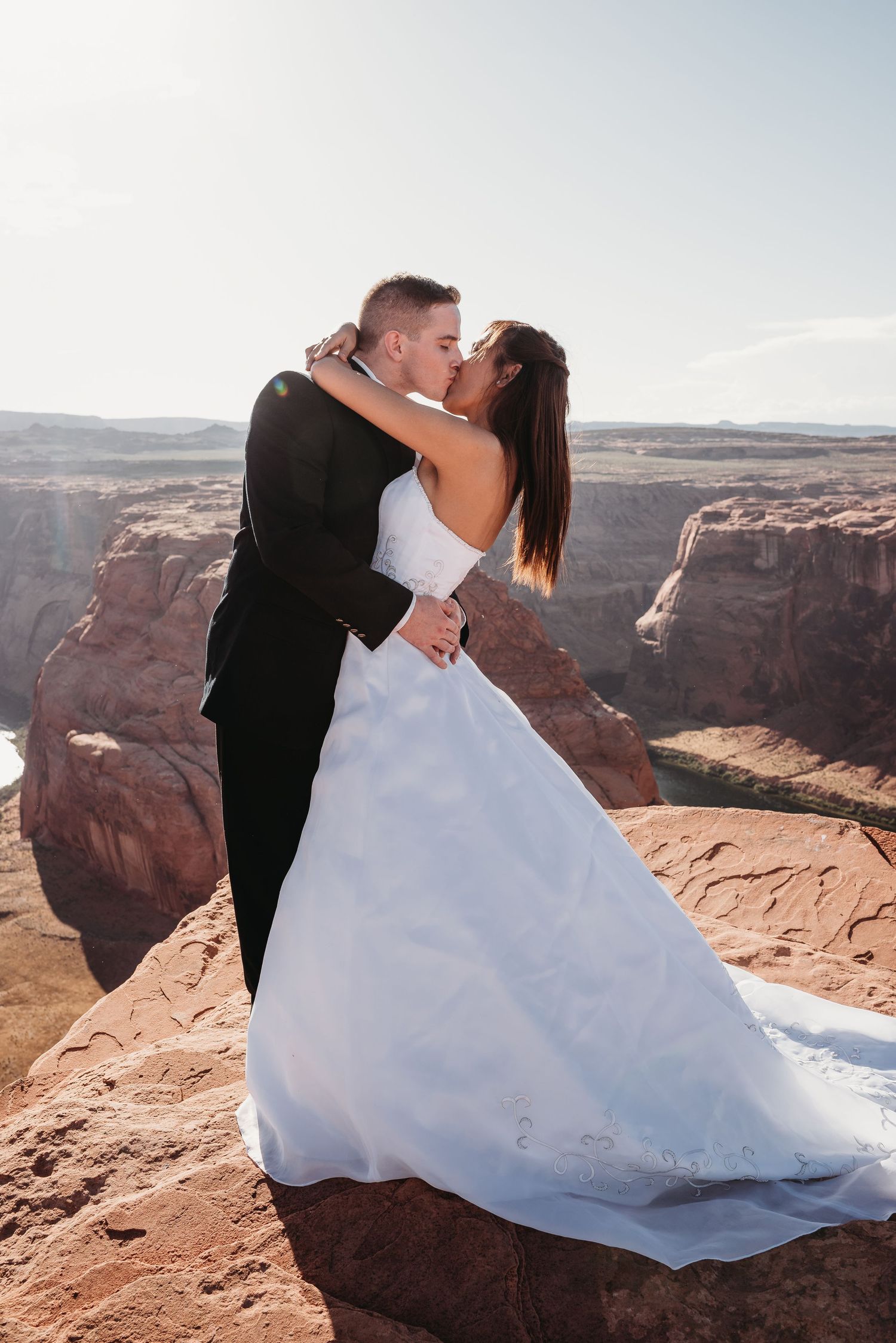 A romantic embrace captured against stunning red rock canyon views.