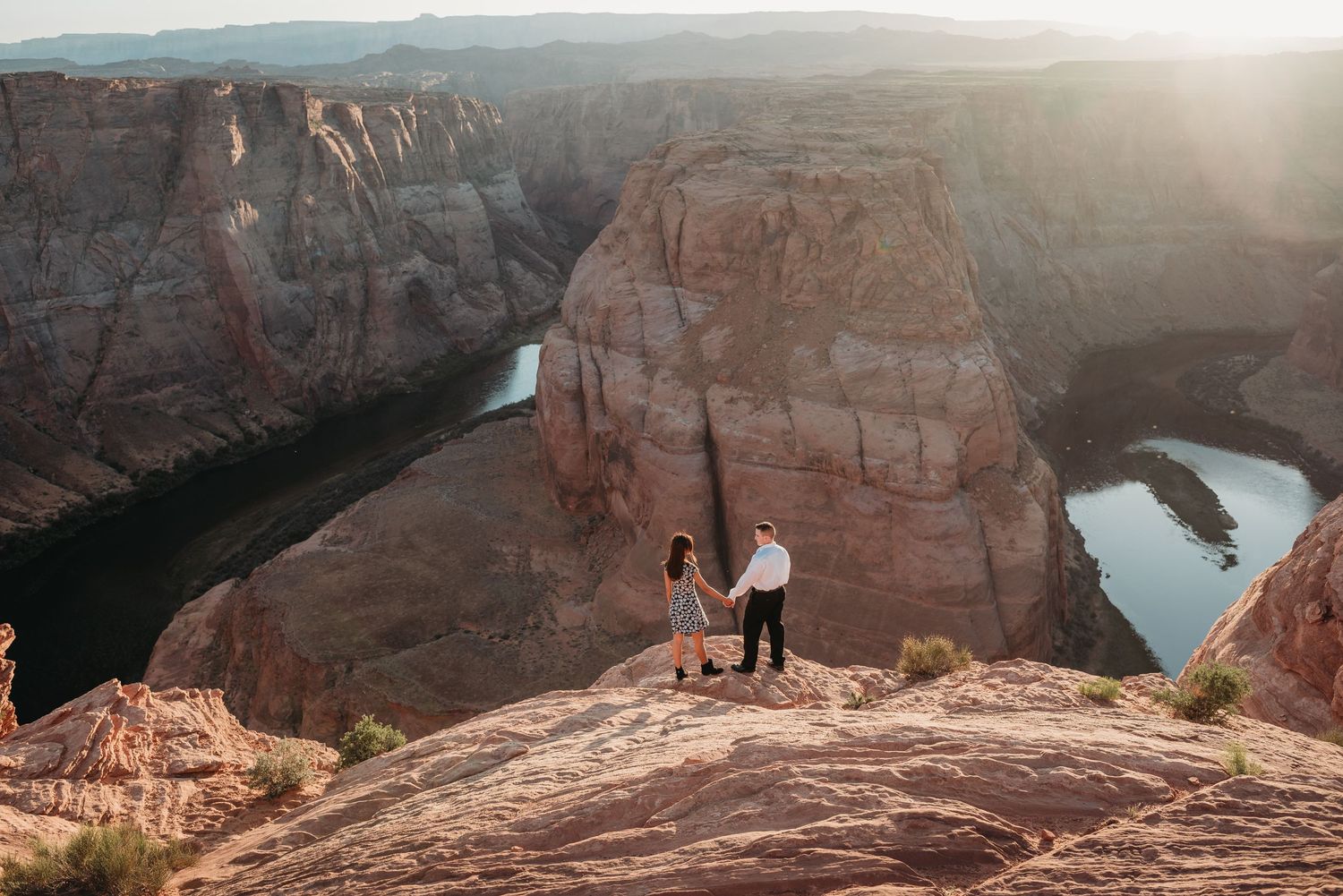 Two figures share a romantic moment on a scenic canyon overlook.