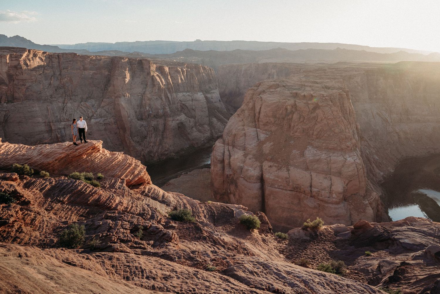 Scenic view of a person sitting on the edge of a red rock canyon during golden hour.
