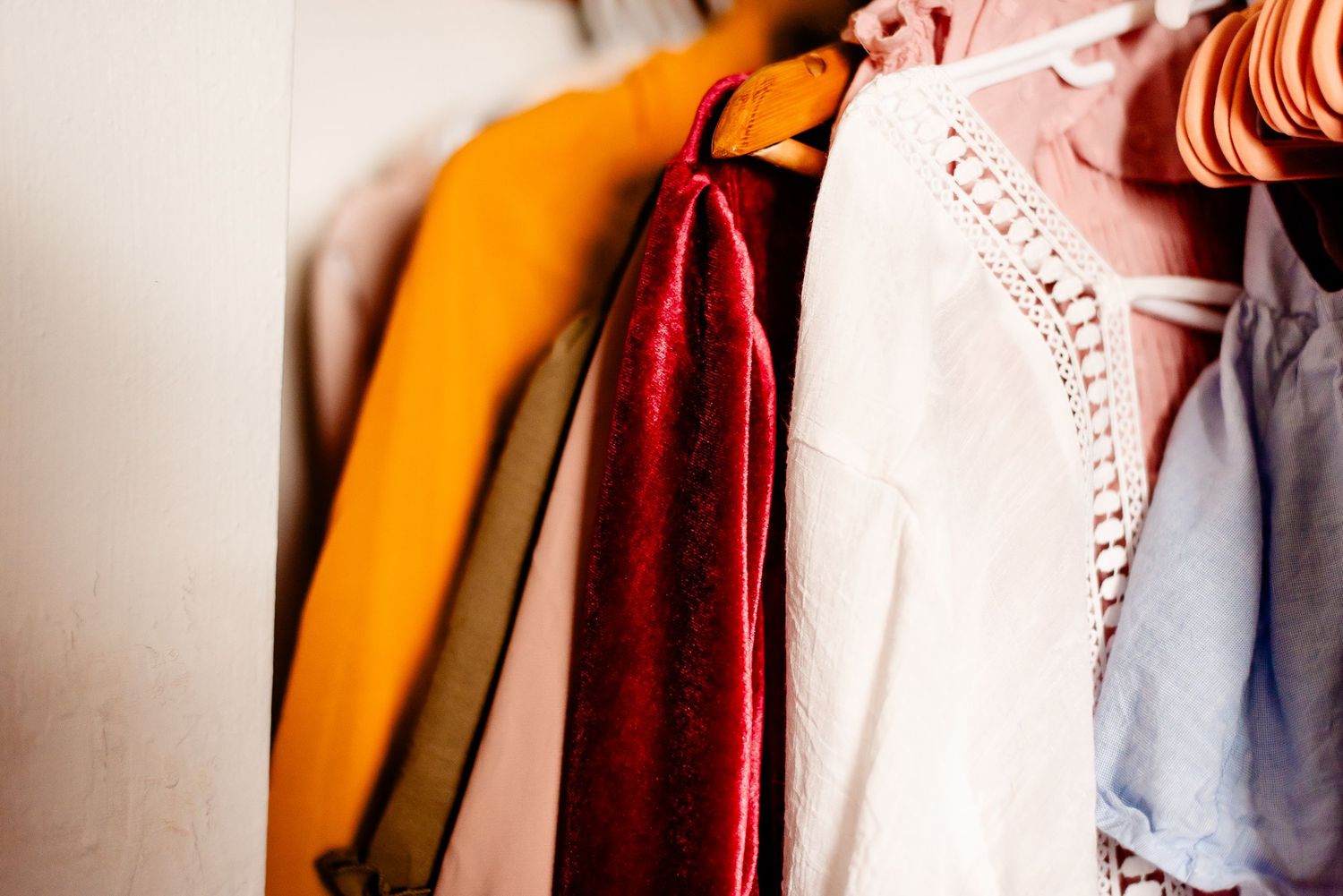 Colorful clothing hanging on a rack showing vibrant orange and burgundy garments.