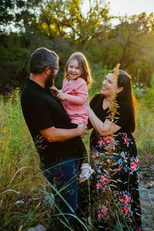 A sunset family portrait among tall grasses with golden light filtering through.