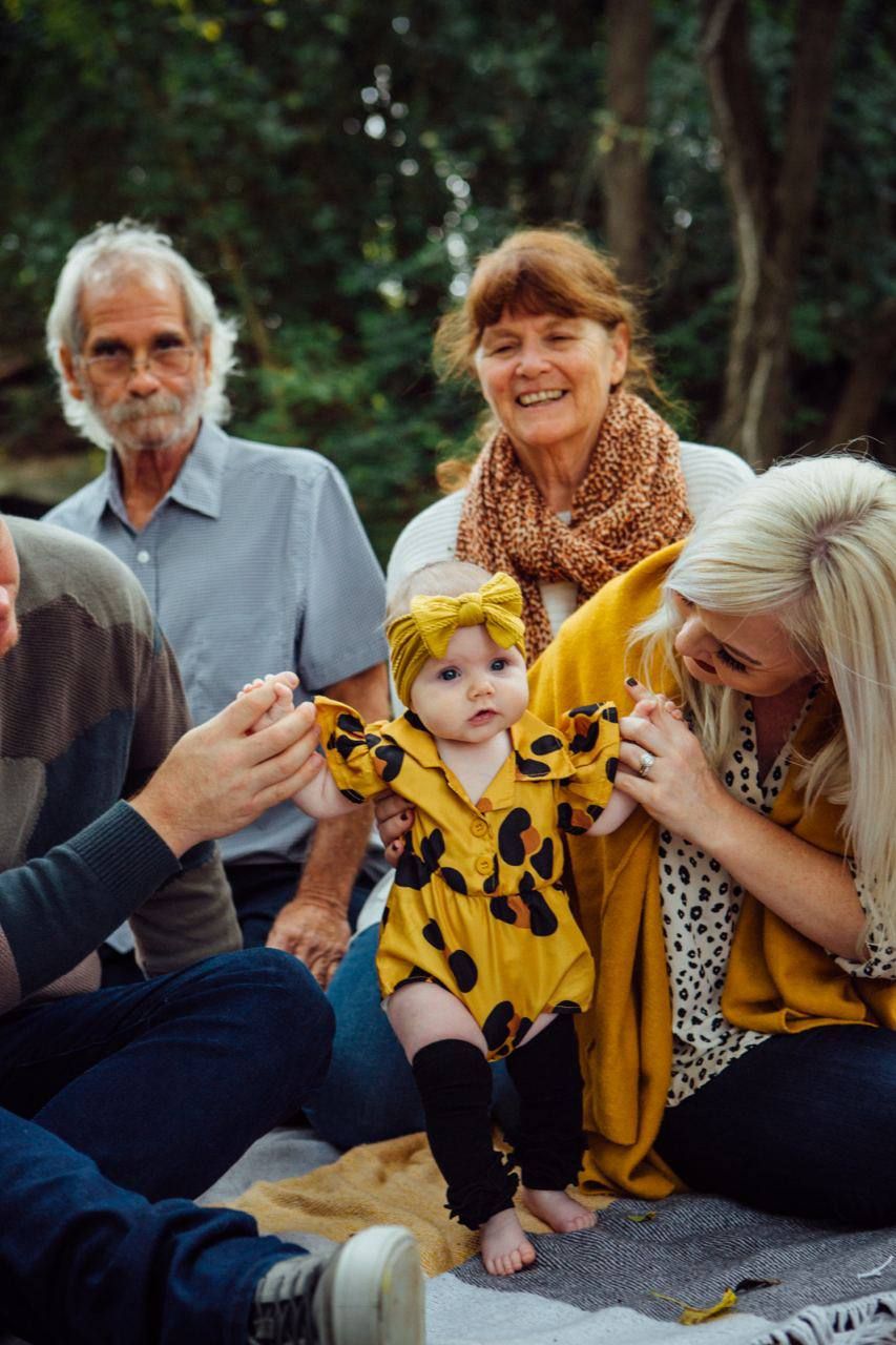 Multi-generational family gathering outdoors with toddler in yellow bee costume.