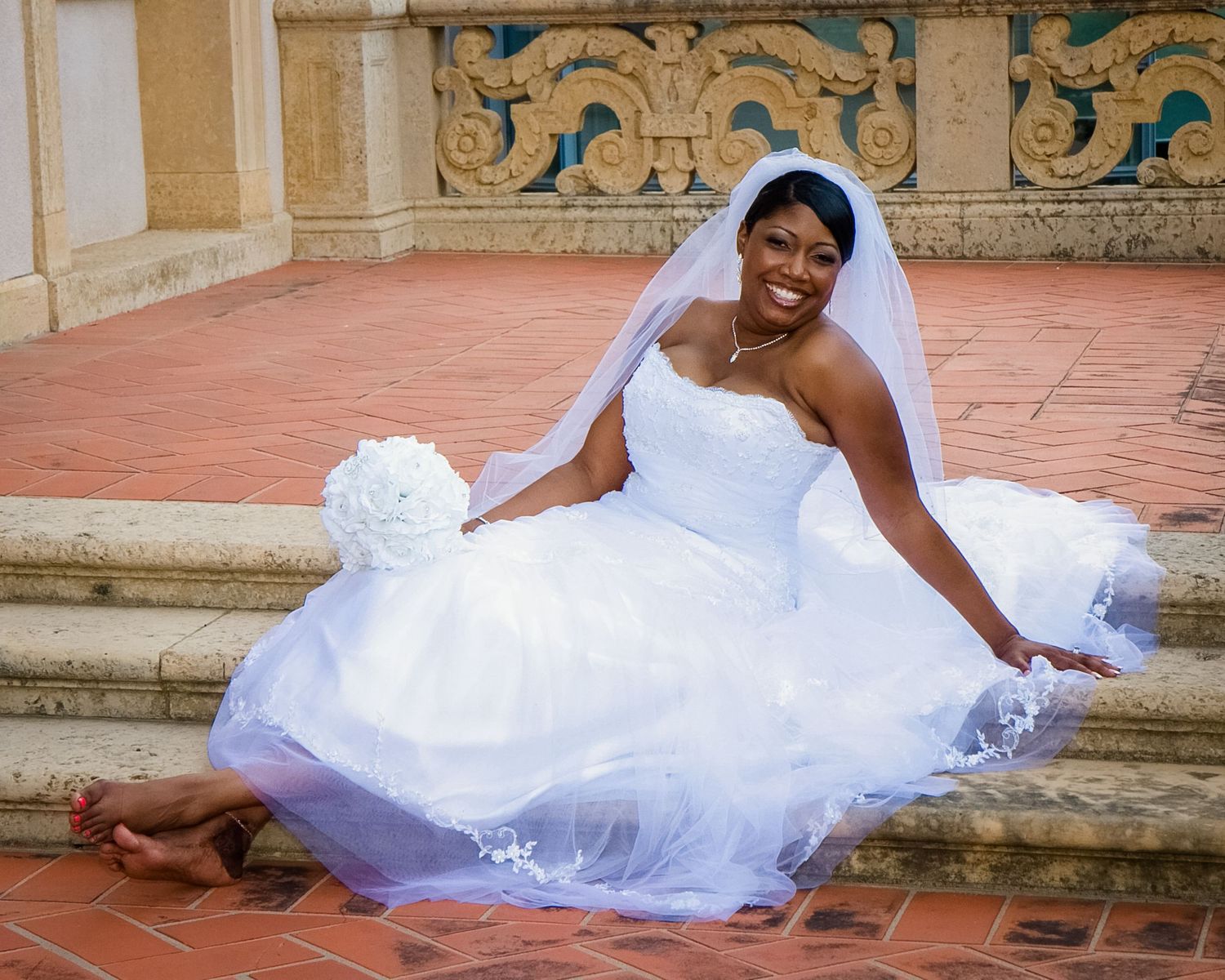 Elegant bridal portrait on rustic brick patio with ornate architectural details.