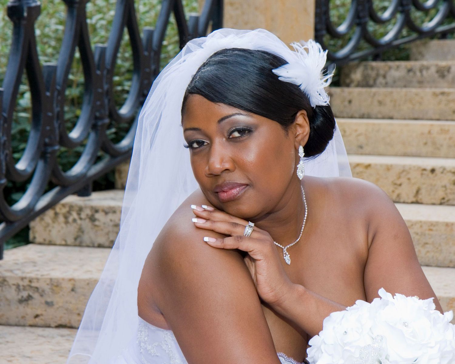 Classic bridal portrait on stone steps with decorative iron railing.