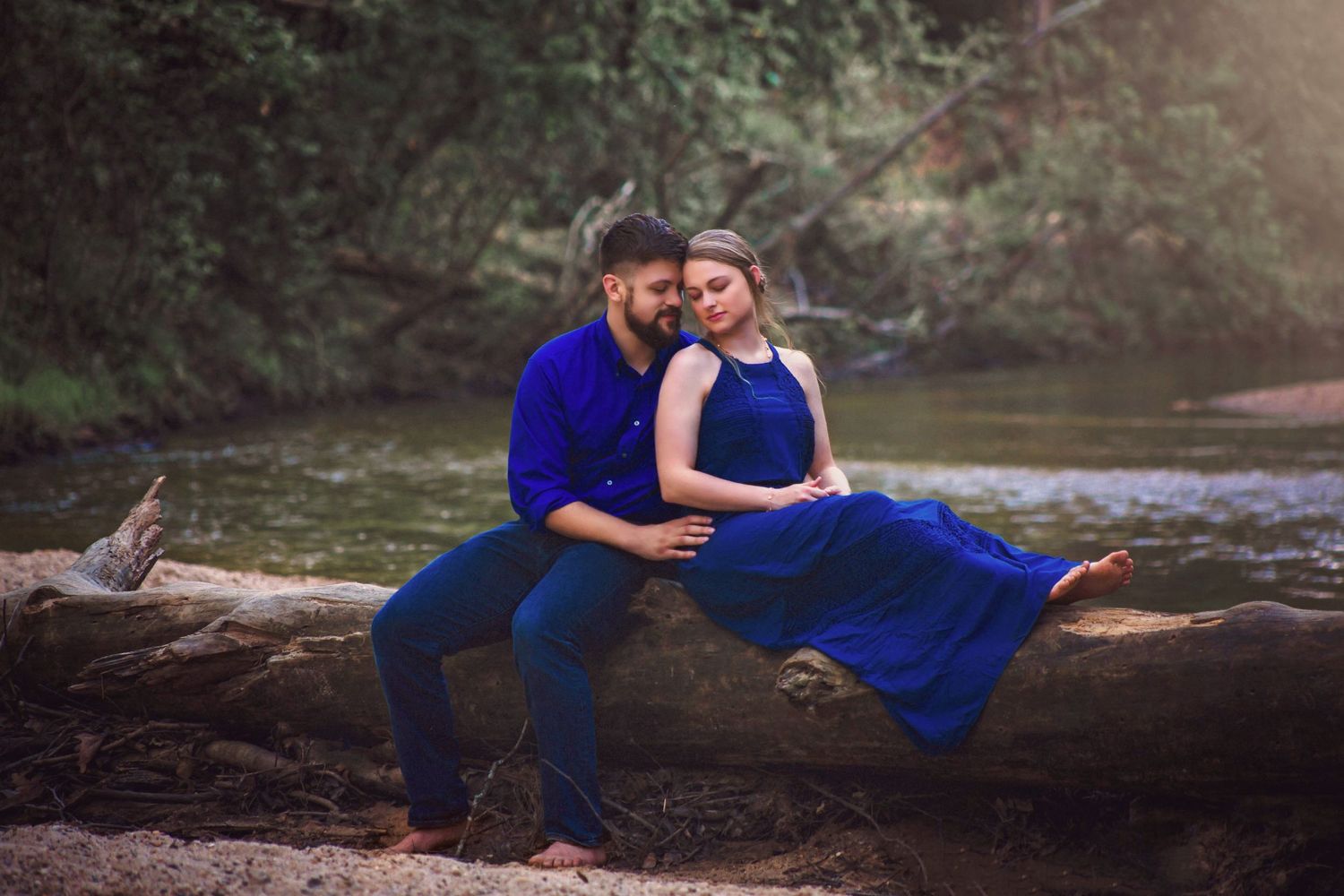 couple in blue outfits on a log on riverbank in Houston, Tx