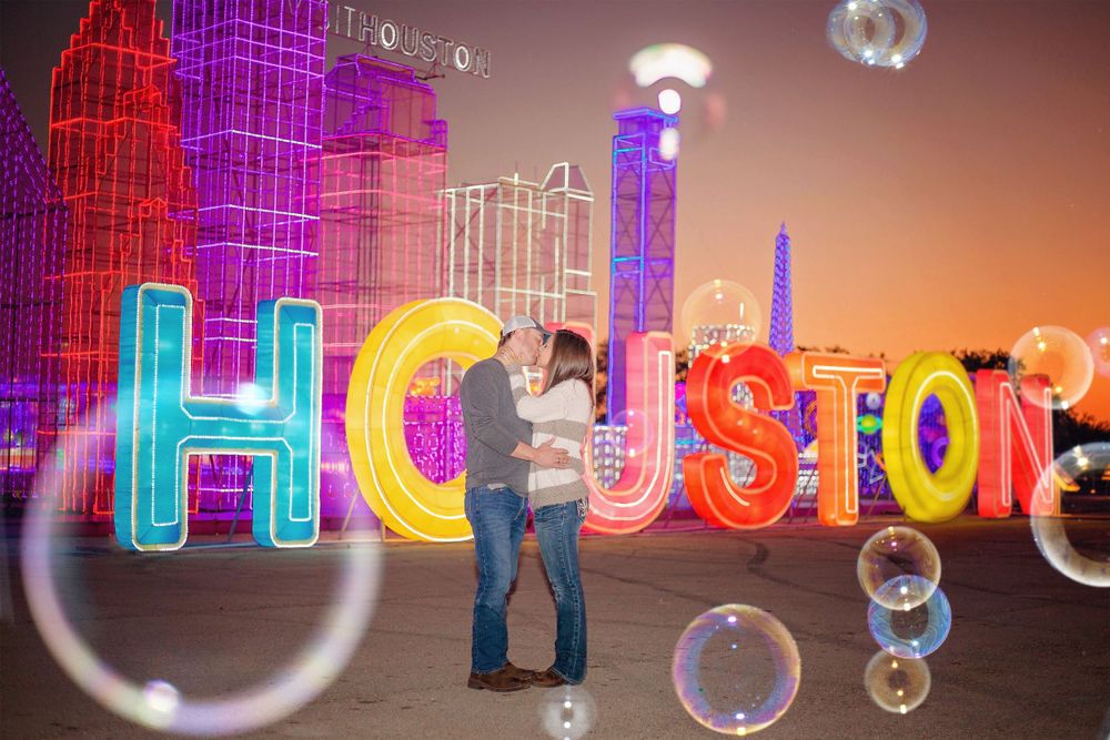 couple embracing in Christmas lights and bubbles in Houston, Texas.