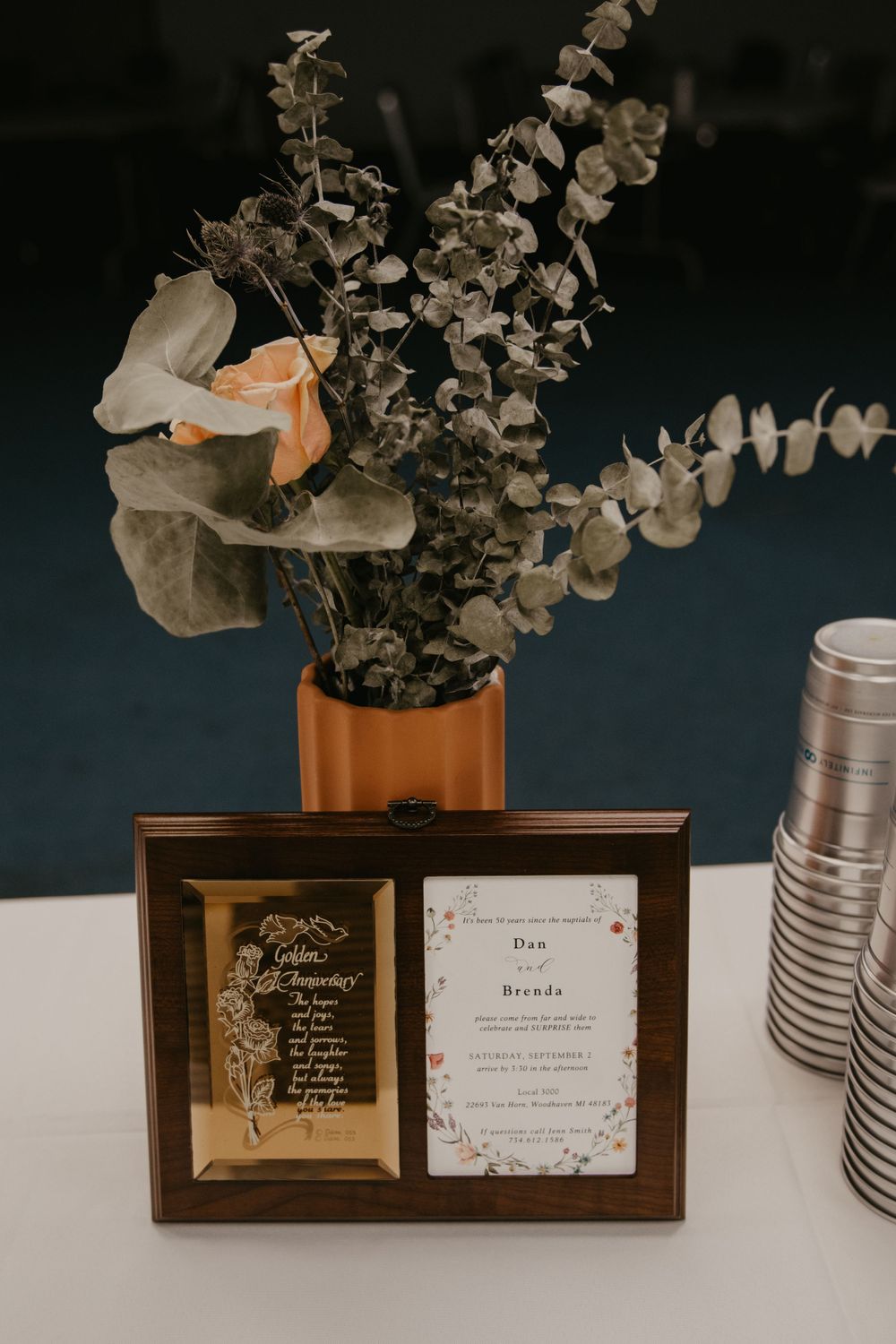 Elegant wedding table display with dried floral arrangement and framed invitation cards.
