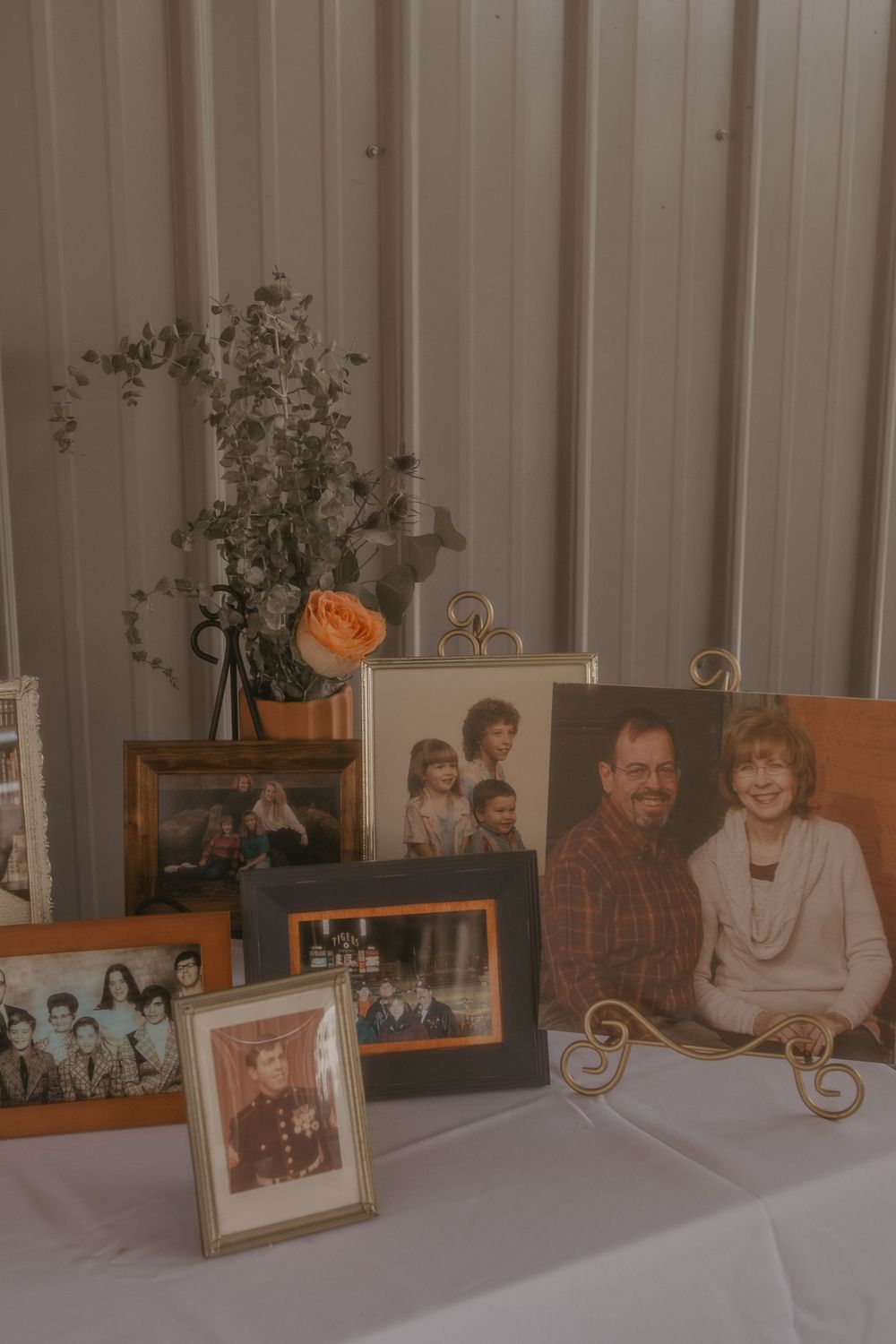 Collection of framed family photos displayed on white tablecloth at anniversary celebration event.