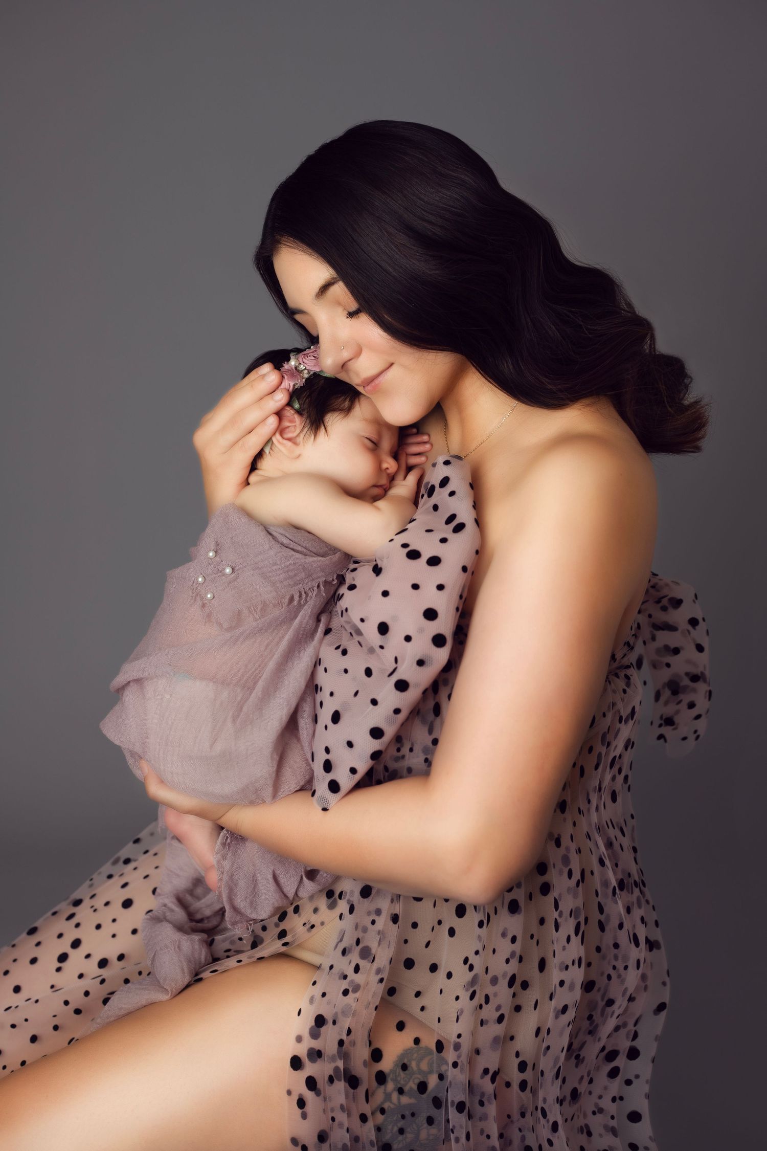 Intimate studio portraits with polka dot dress against dark grey background.