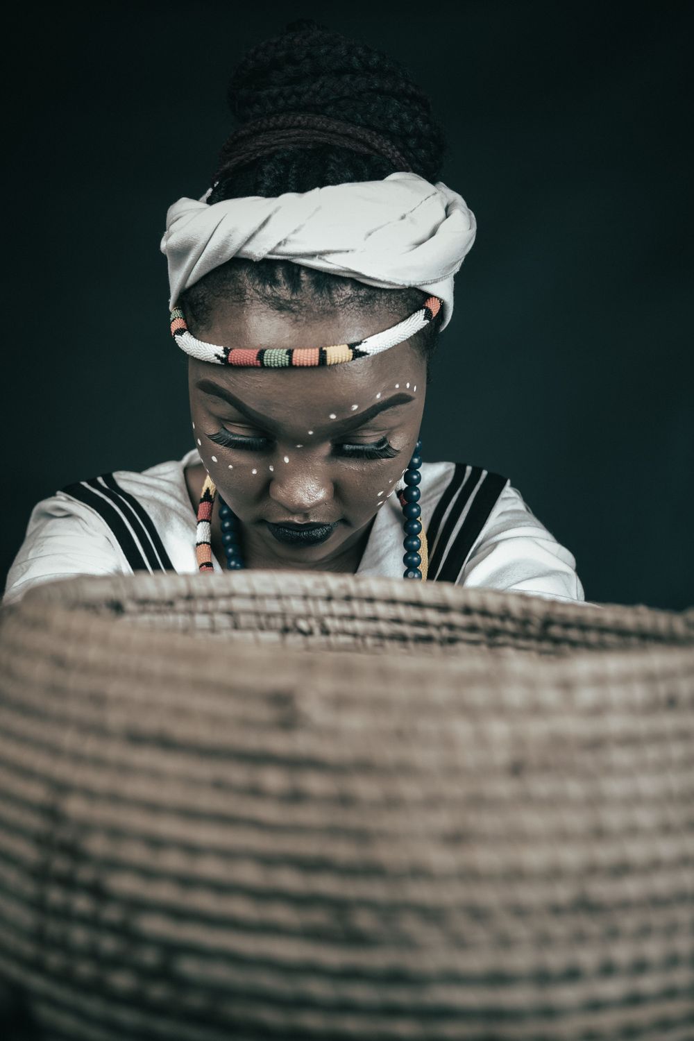 Traditional photography, celebrating heritage day, a lady kneels down and offers a basket full of gifts or food, respectifully.