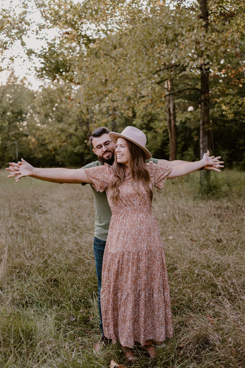 A person in a pink dress spreads their arms joyfully in a sunlit field.