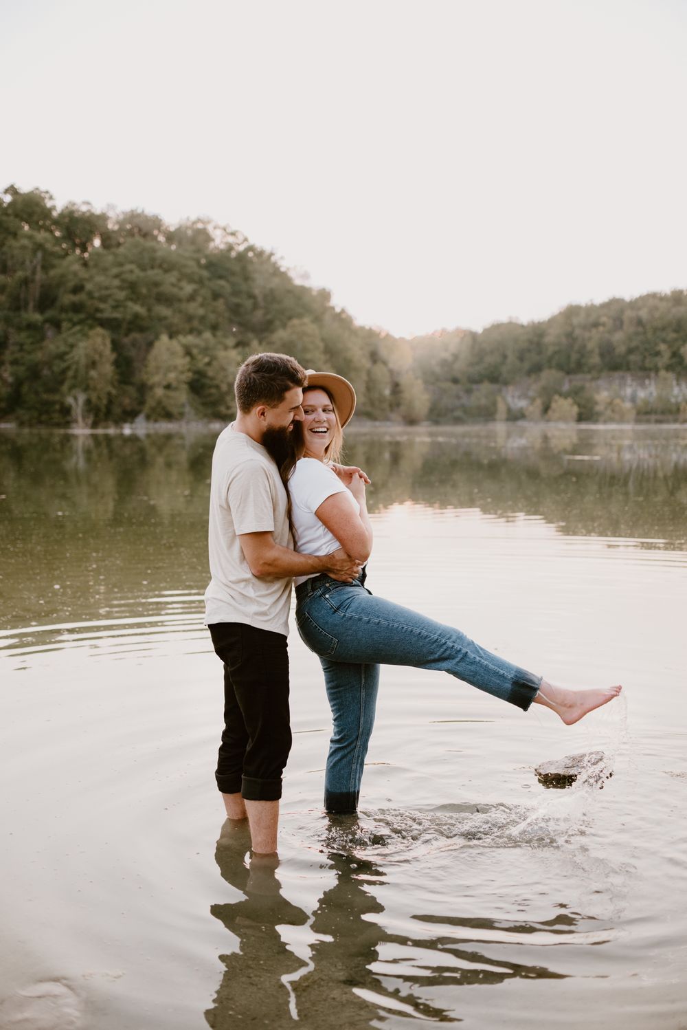 A playful couple splashes in shallow water during sunset.