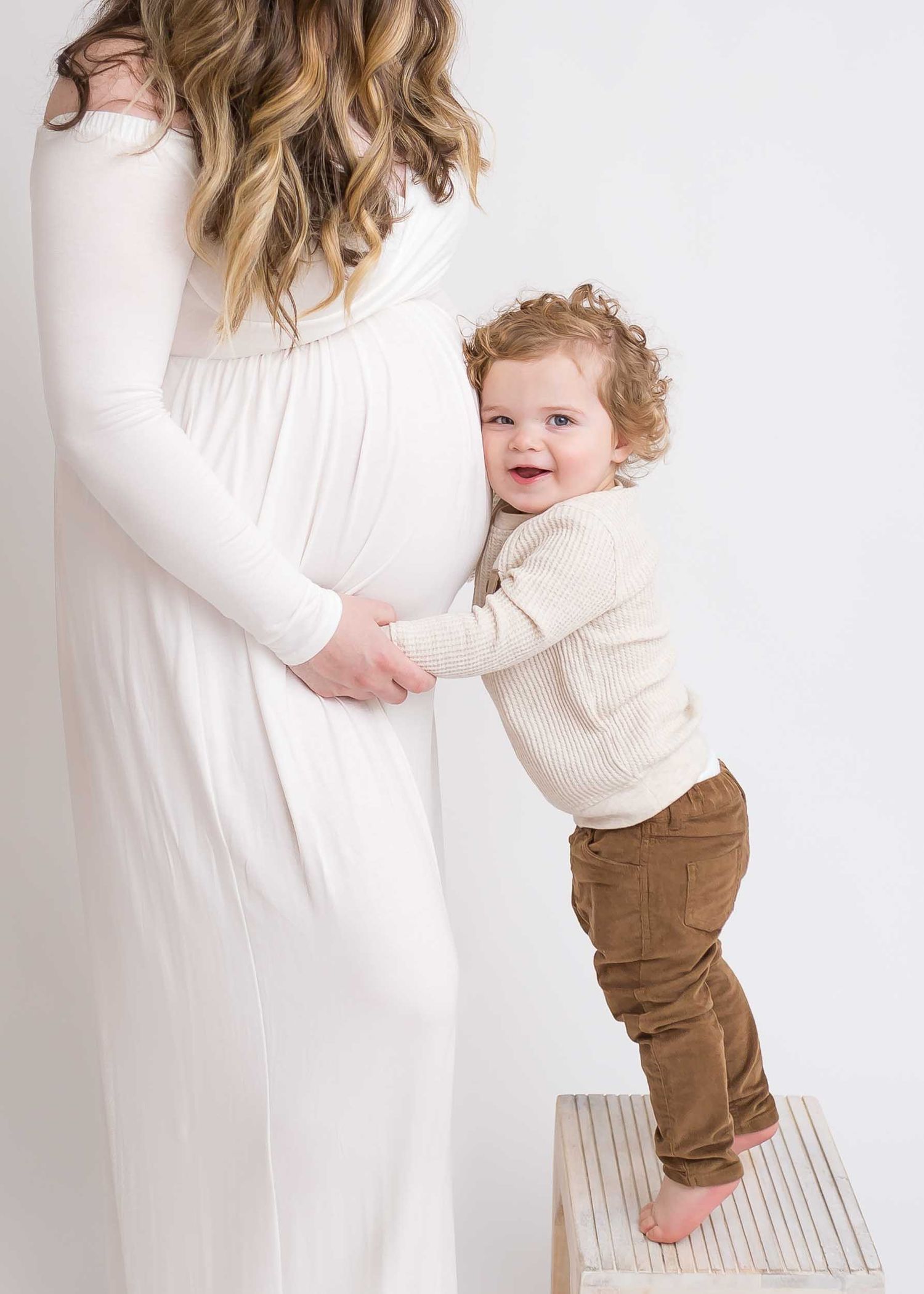 expectant mother and sone smiling at camera, white dress, newborn family pictures chattanooga photo studio, family photo