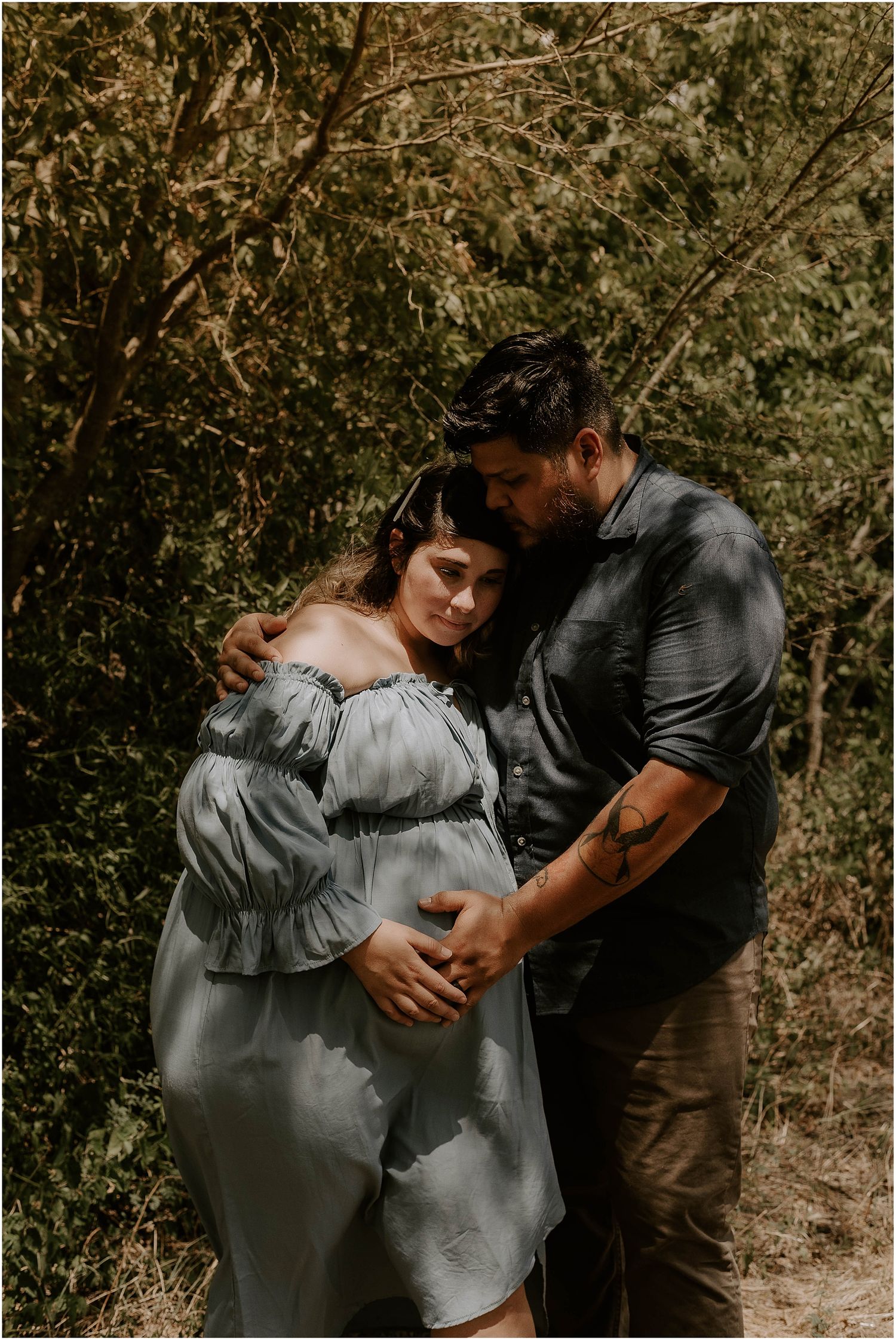 Intimate maternity photoshoot featuring a couple embracing in a dreamy outdoor setting with soft lighting.