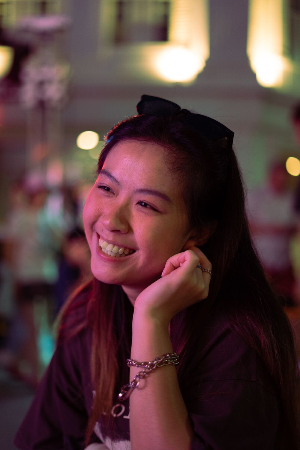 A nighttime portrait of someone enjoying an evening event with soft bokeh lights in the background.