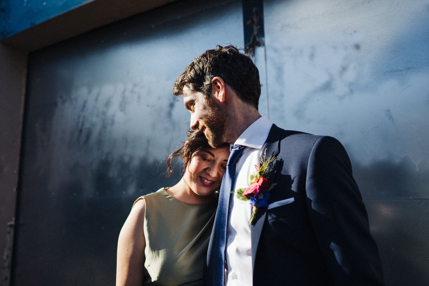 A tender moment between newlyweds against an industrial backdrop.