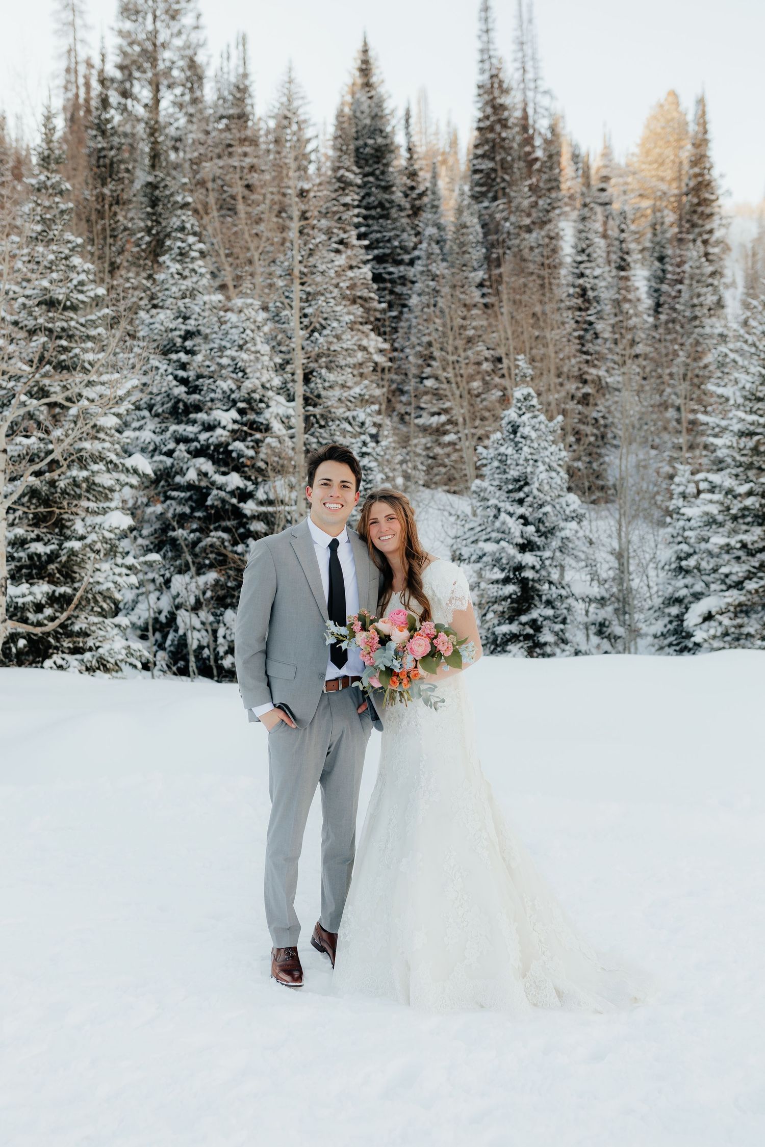 Bride and Groom smile with flowers in pine tree mountain
